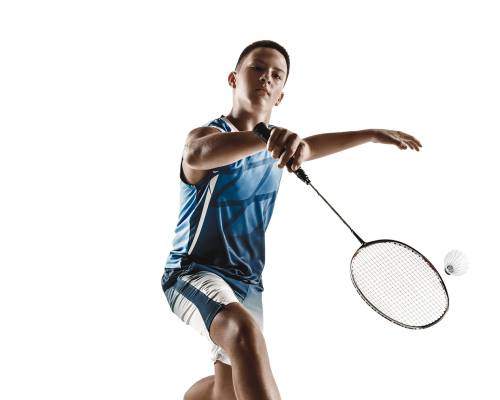 Little boy playing badminton isolated on white studio background. Young male model in sportwear and sneakers with the racket in action, motion in game. Concept of sport, movement, healthy lifestyle.