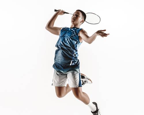 Little boy playing badminton isolated on white studio background. Young male model in sportwear and sneakers with the racket in action, motion in game. Concept of sport, movement, healthy lifestyle.